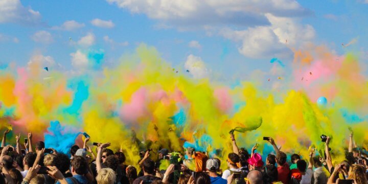 group of people throwing dry paint into the air in a color race on a sunny day