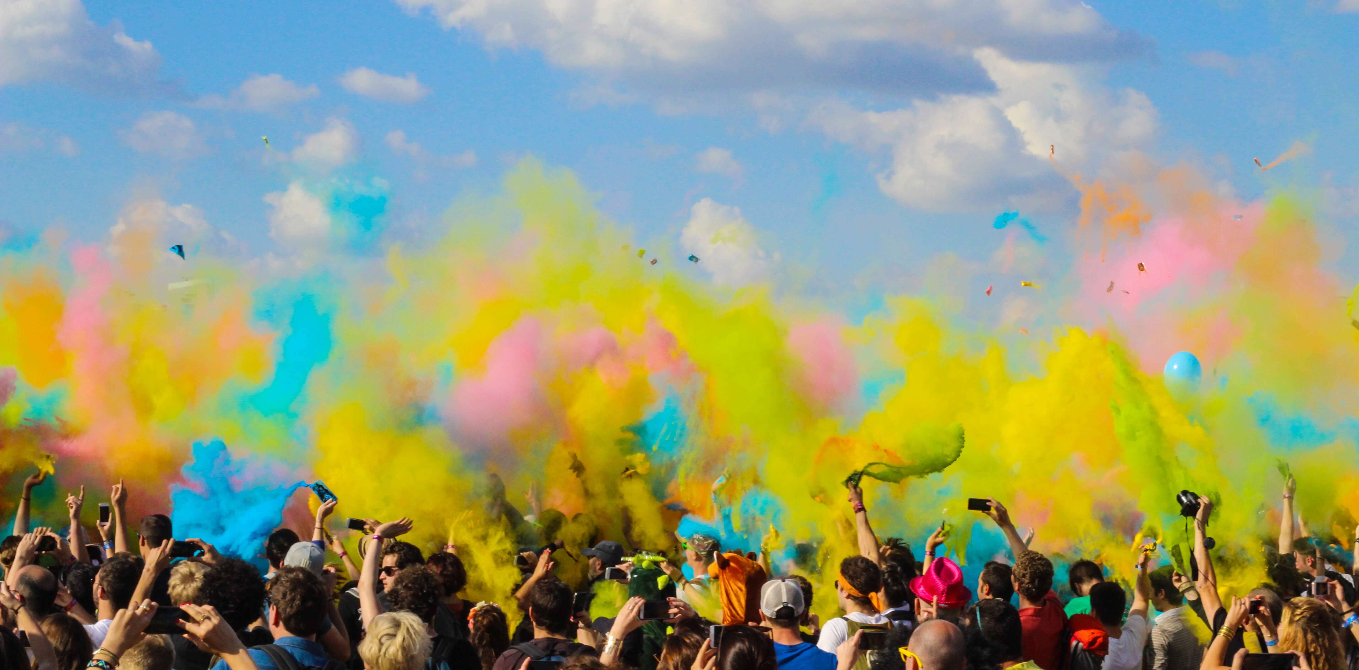 group of people throwing dry paint into the air in a color race on a sunny day