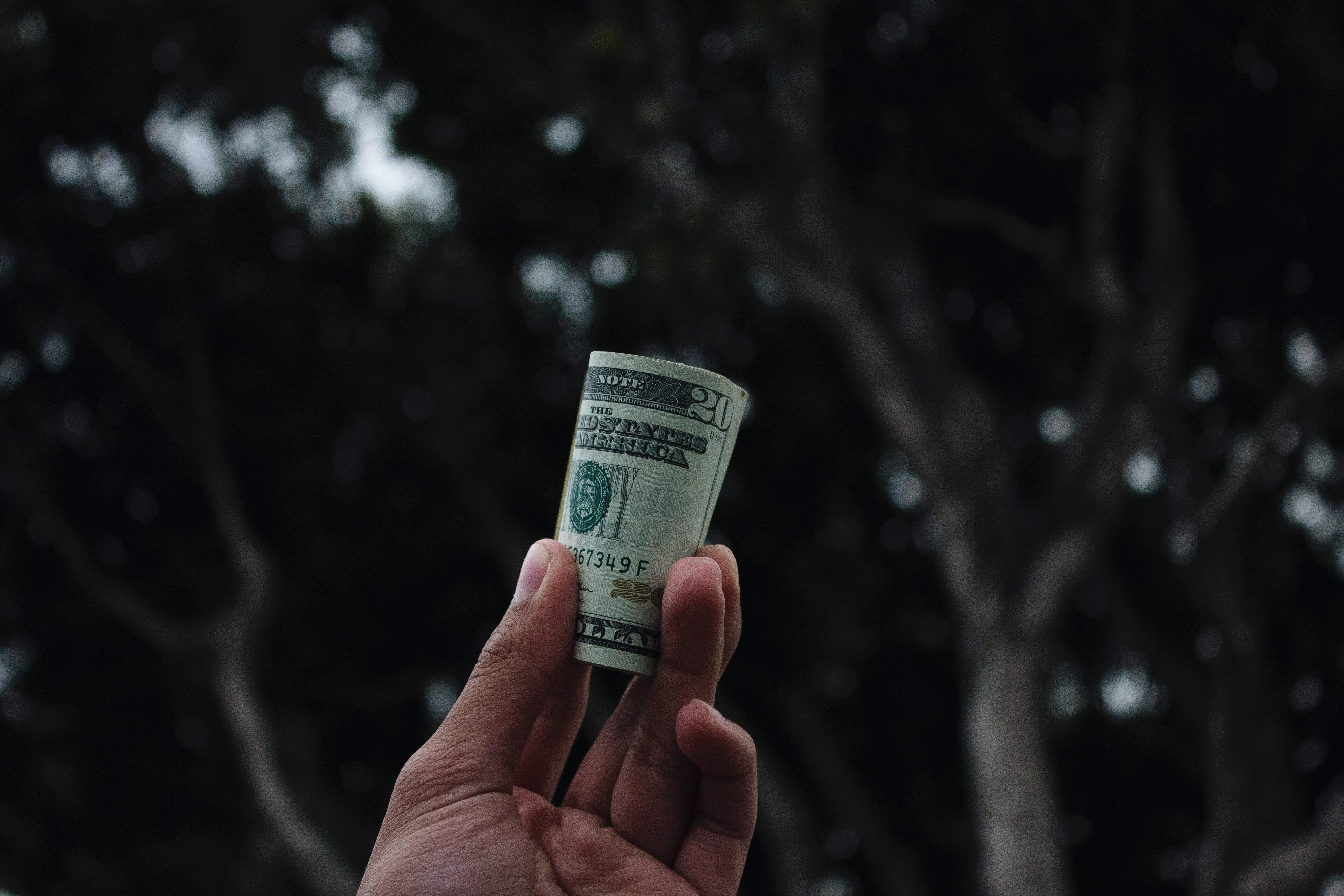 A hand holding a stack of $20 bills 