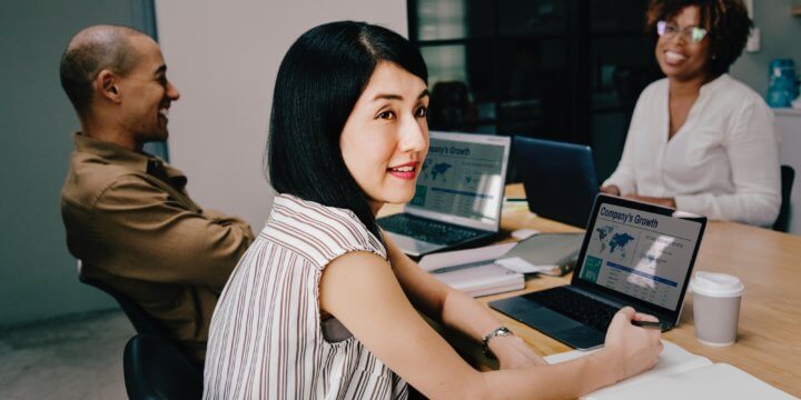 Woman sitting at a table with two colleagues reviewing social media reporting