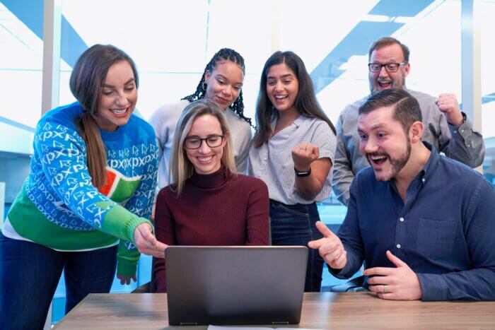 Teammates gathered around a computer