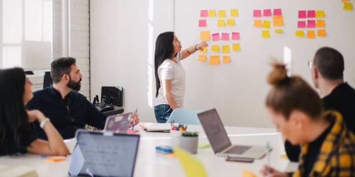 A group of people gathered around a white table and wall of colorful post-its