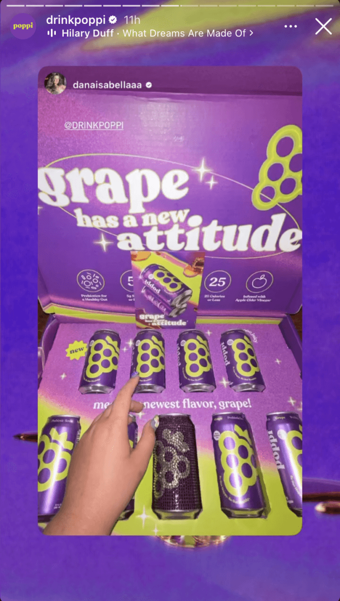 An Instagram Story frame from beverage brand Poppi that displays a box full of its grape flavored soda. The Story also includes audio of Hilary Duff's song "What Dreams Are Made Of."