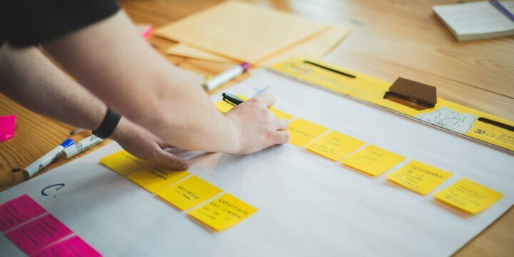 pink and yellow sticky notes lined up on a table to plan a content marketing strategy