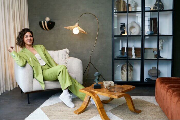 Social media influencer Megan in a pale green suit relaxing on a couch 